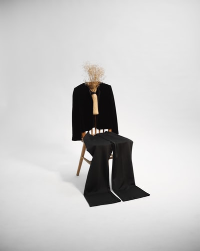 女人在黑色外套坐在棕色的木椅上
